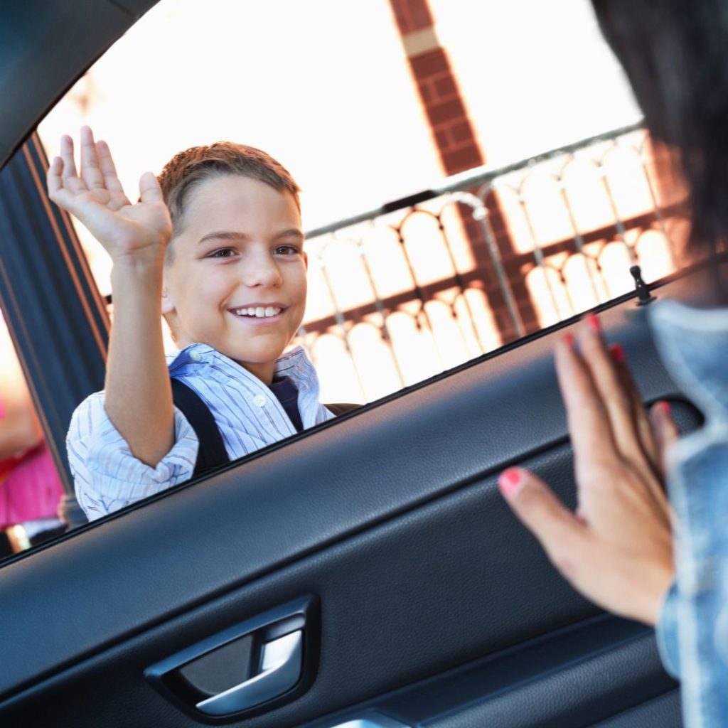 photo of a son waving to his mom after getting dropped off for school